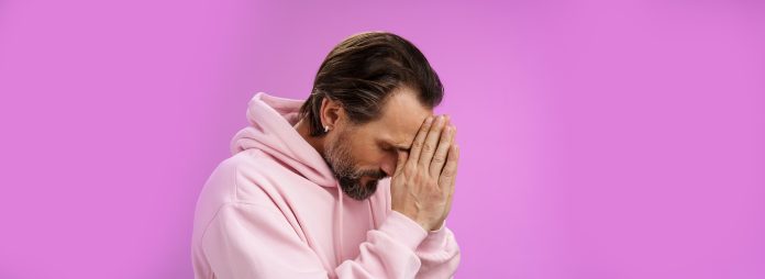 Concerned upset man supplicating asking god mercy help praying bow head close eyes hold hands pray hopefully waiting miracle worried wife health, standing sadness purple background