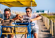 Mature man with teenage son riding cart on road during vacation. Father son enjoying leisure time on holidays. Father with son having fun driving trolley cart on holiday