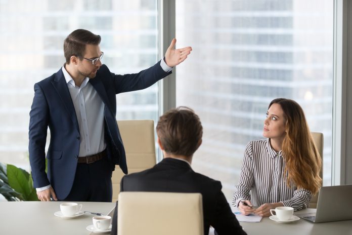 Mad male worker asking female partner leave meeting