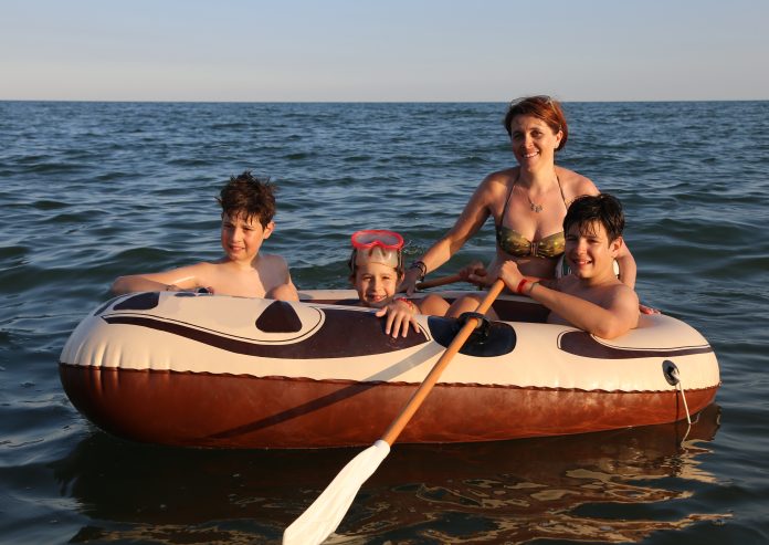 three brothers with mom on the dinghy sailing on the sea